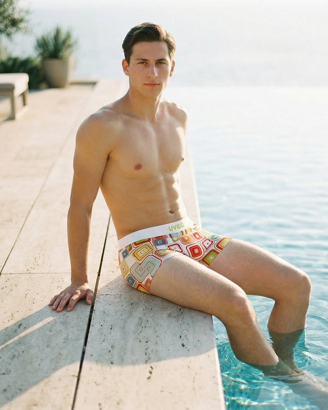 homme assis sur bord de piscine en boxer moulant