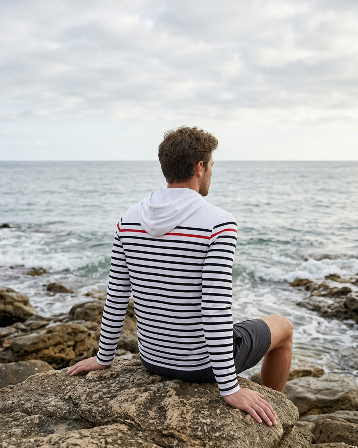 homme assis sur un rocher avec un rashguard