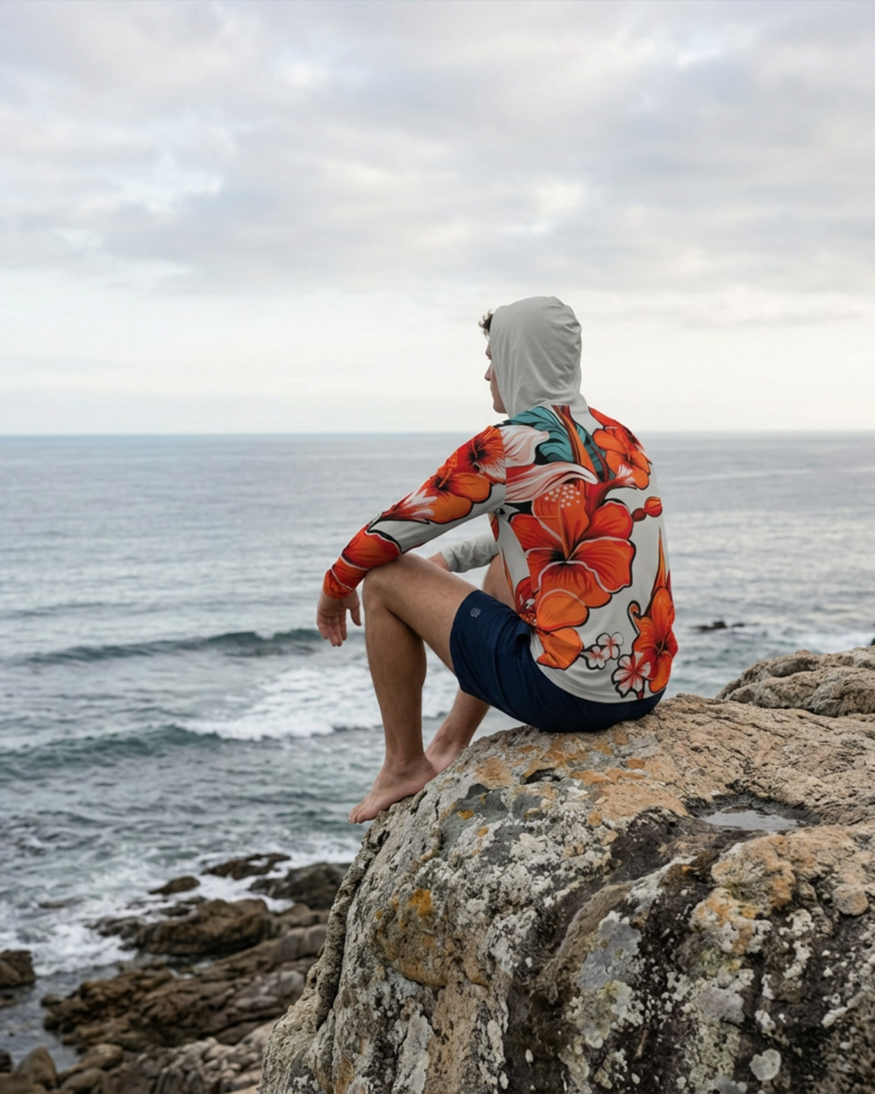 homme assi sur un rocher avec un rashguard 