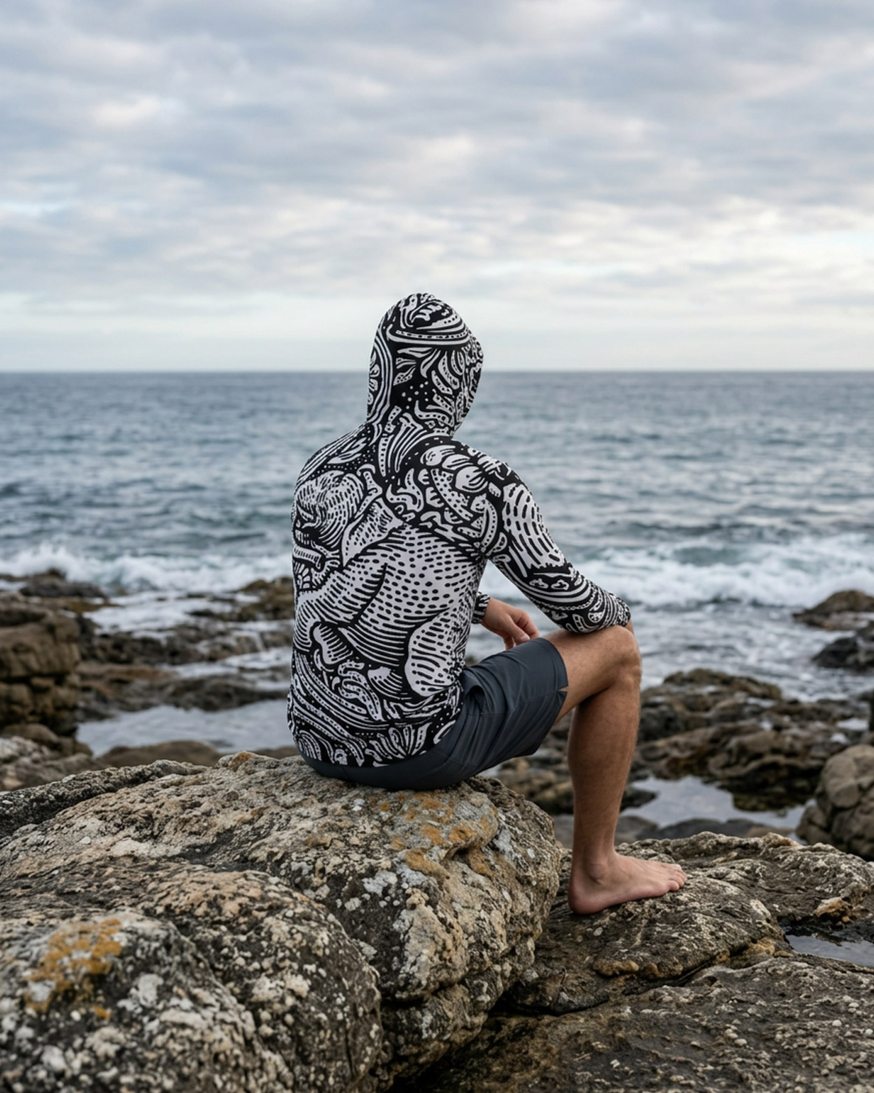 homme assi sur un rocher avec un rashguard