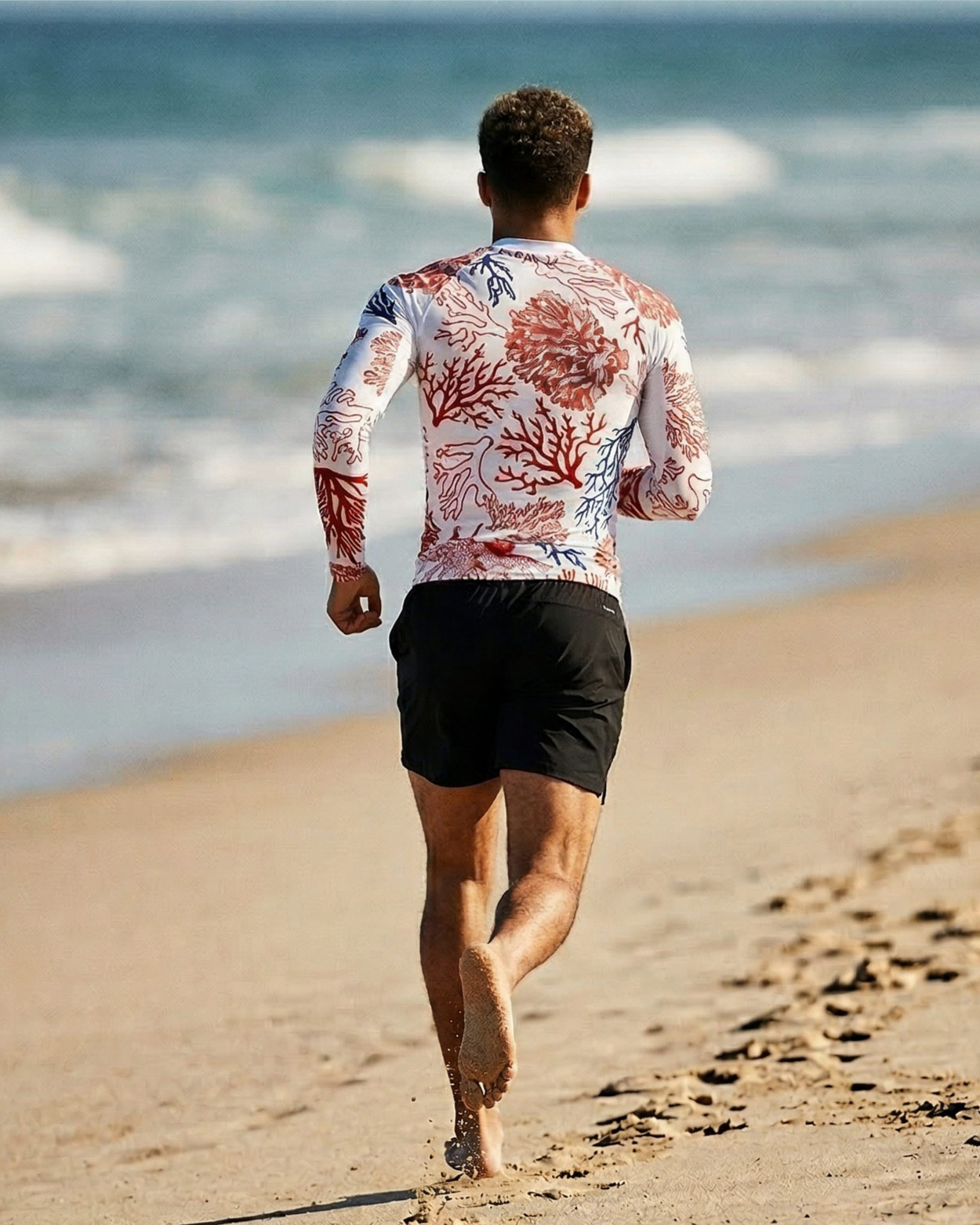 jeune homme en tee shirt uv courant sur la plage 