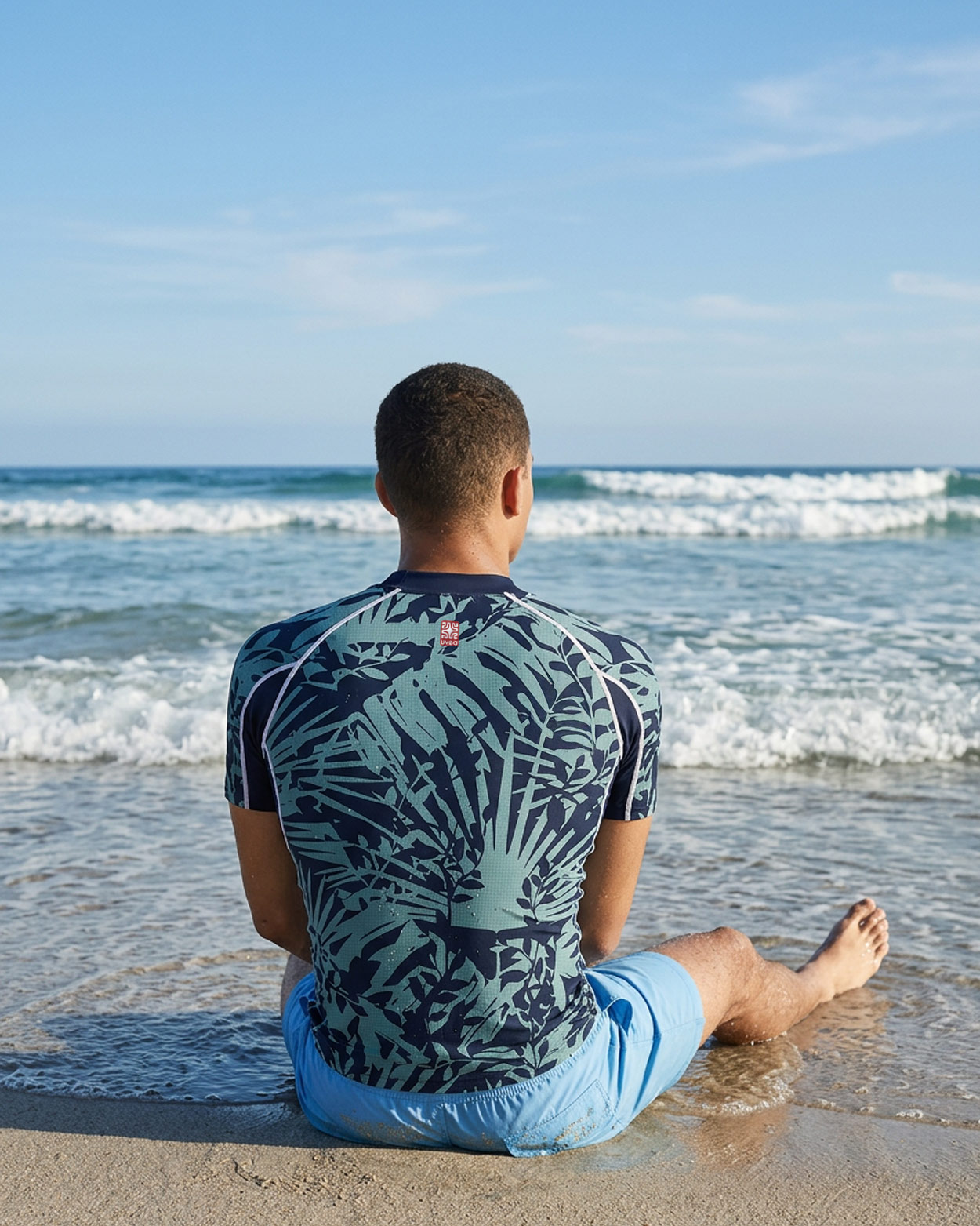 homme assi sur le sable avec un tee shirt uv manche courte
