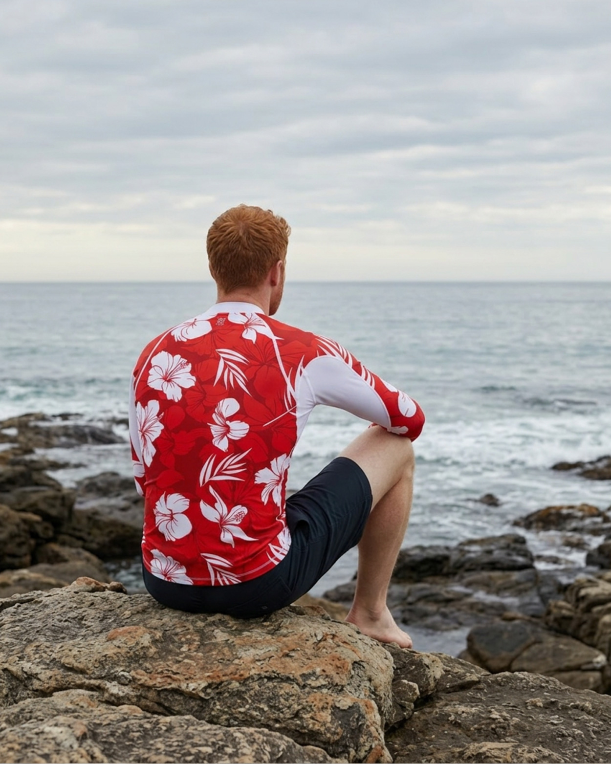 homme portant un tee shirt anti uv rouge sur un rocher de dos