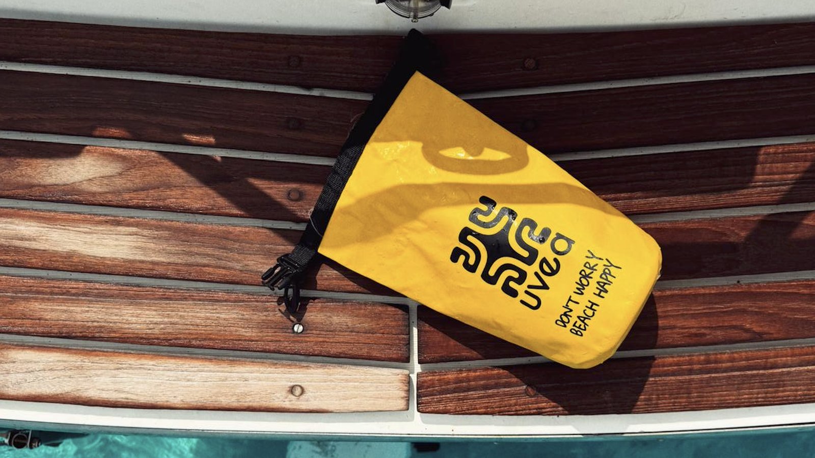 Gelber UVEA 2L Dry Bag auf einem Bootsdeck
