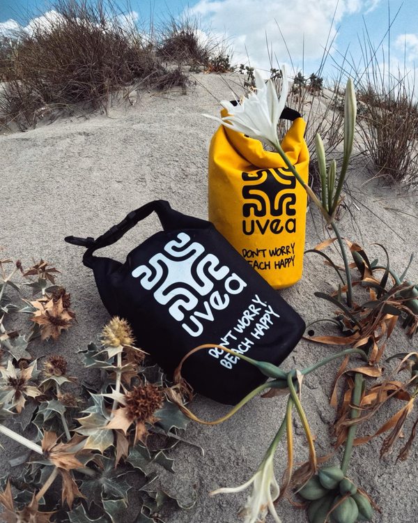 Schwarzer und gelber UVEA Dry Bag in den blühenden Dünen