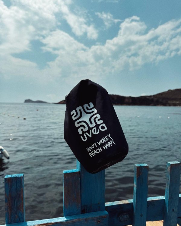 Schwarzer UVEA Dry Bag an einem Zaun am Meer